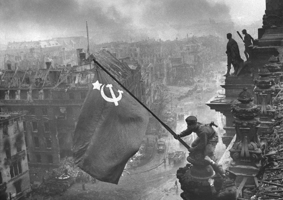 Red Army soldiers hoisting a hammer-and-sickle flag over the Reichstag in Berlin, 1945.